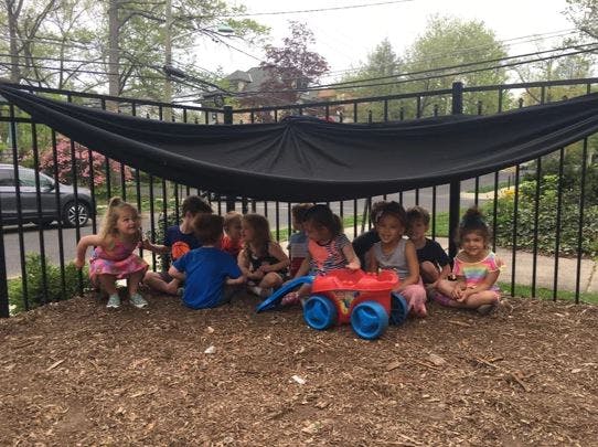 Children playing under a black tarp