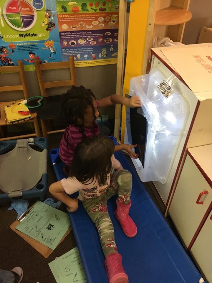 Two children playing with a clear plastic tube in a classroom