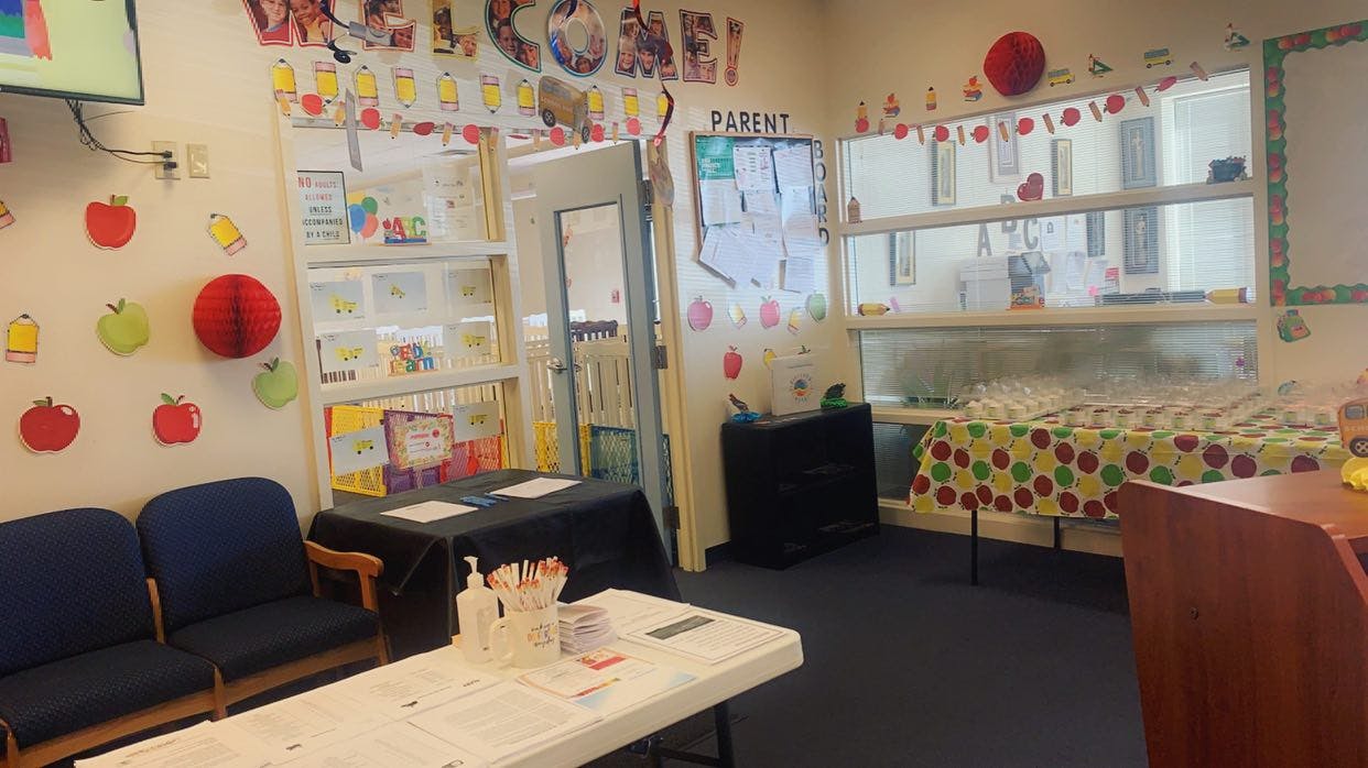 Classroom decorated with apples and pencils, tables with school supplies and cups