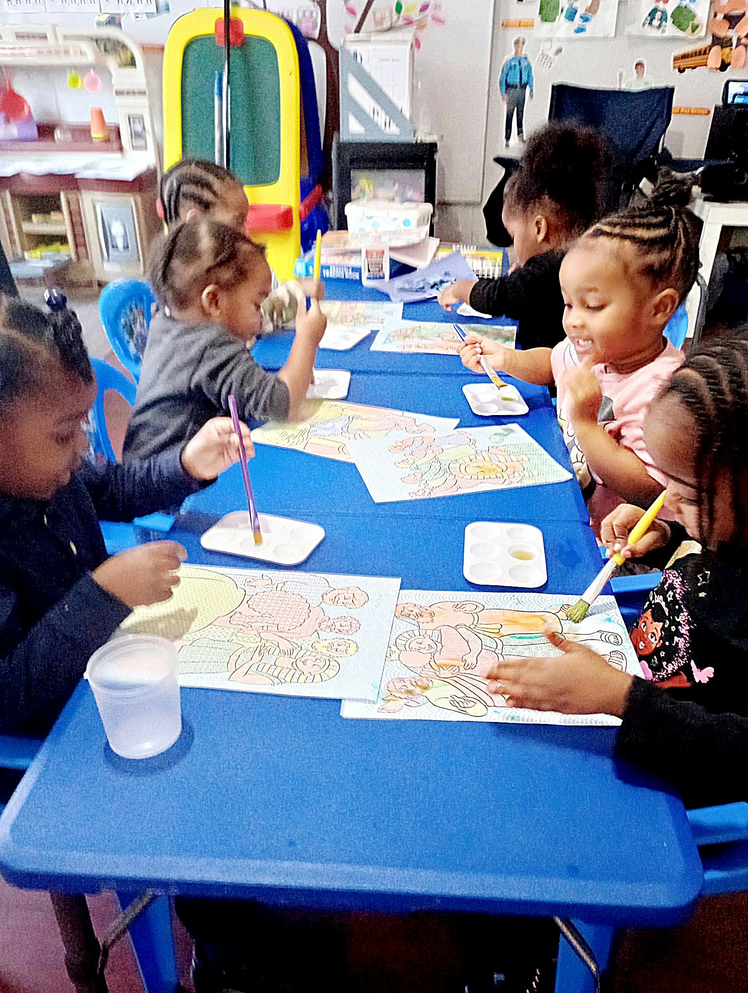 Children painting at a table in a classroom