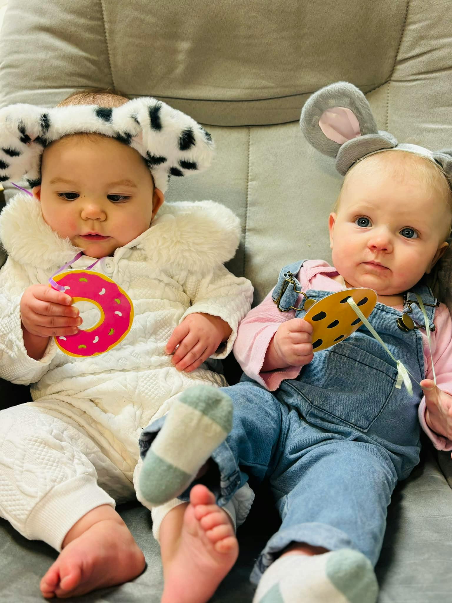 Two babies wearing animal ear headbands and holding toy food