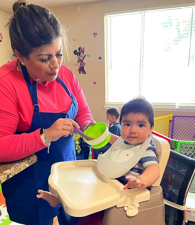 Person feeding a child in a high chair