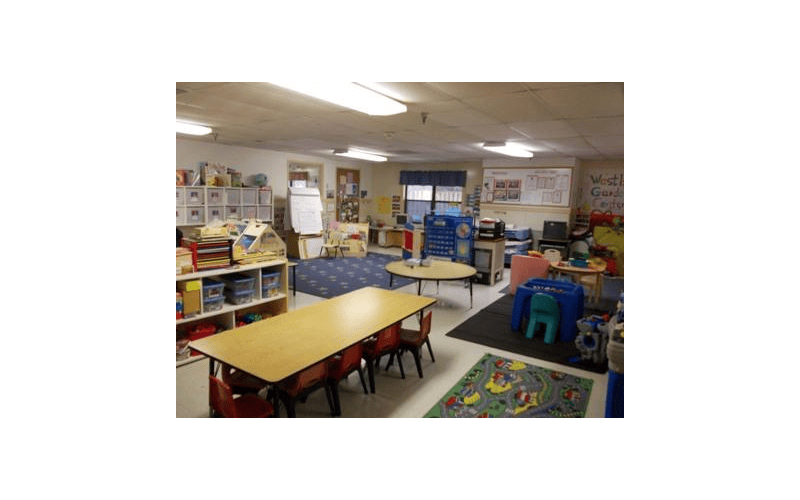 Classroom with tables, chairs, shelving units, and a calendar board