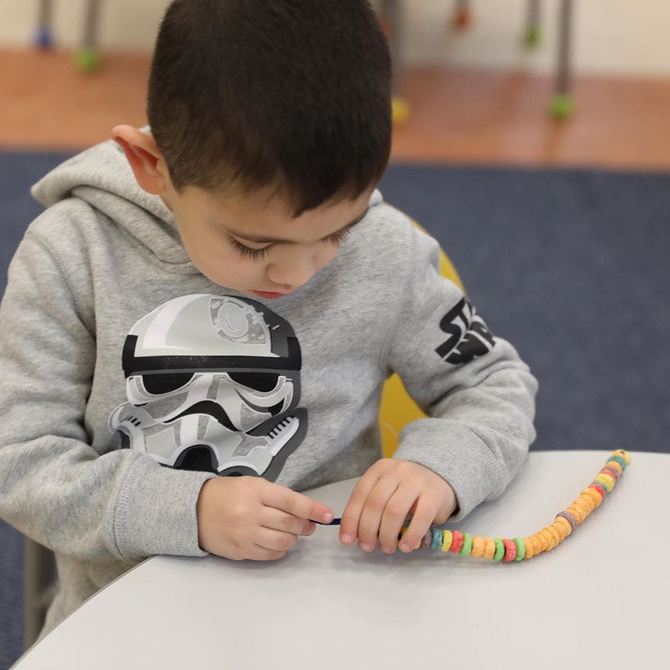 Child stringing colorful beads