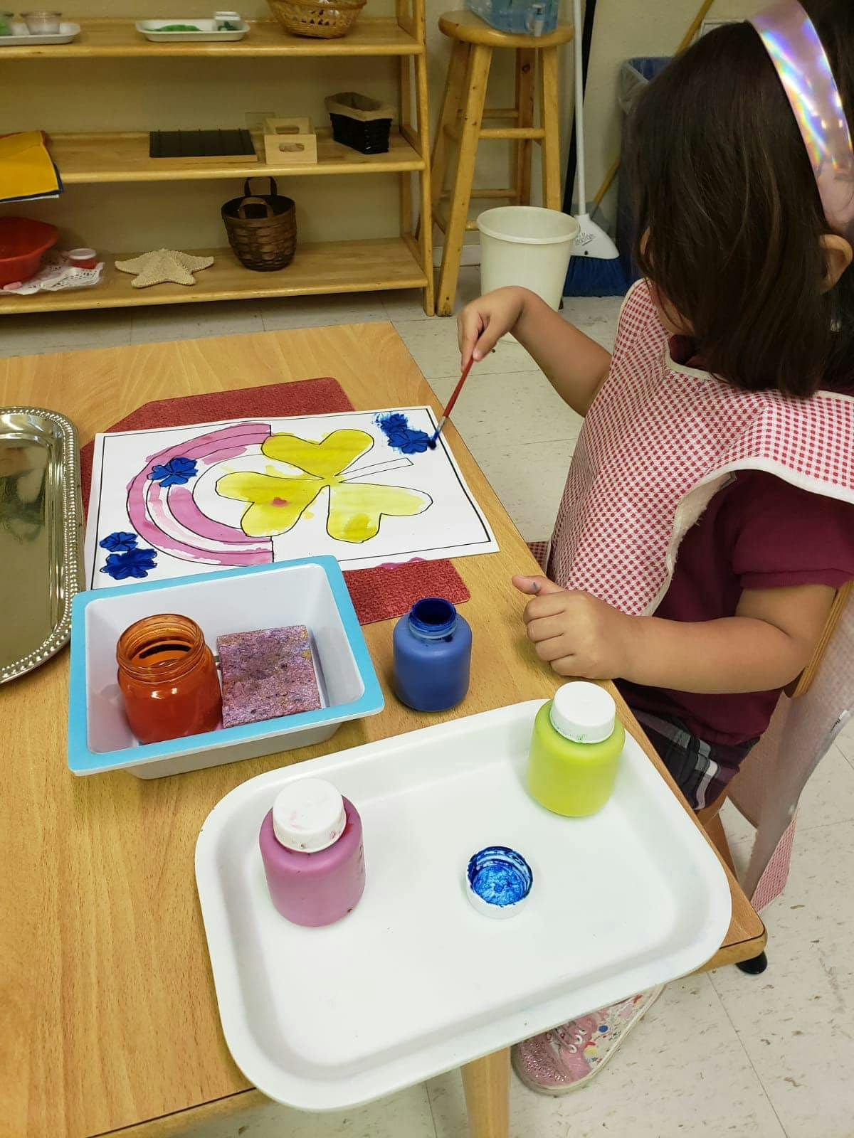 Child painting a picture with a brush at a table