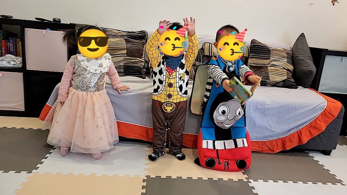 Three children in costumes, one dressed as a princess, one as a cowboy, one as a train