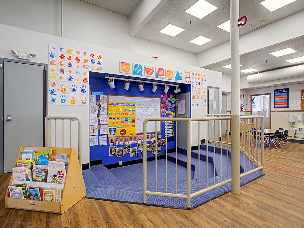Classroom with a small stage and colorful handprint decorations on the wall