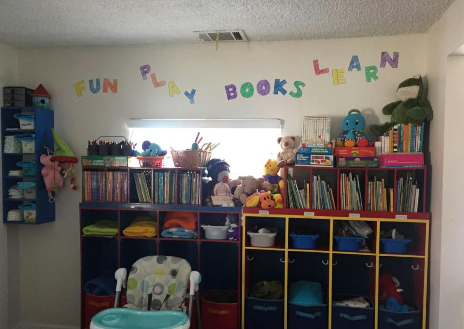 Child's room with shelves of books and toys, text on wall says "FUN PLAY BOOKS LEARN"