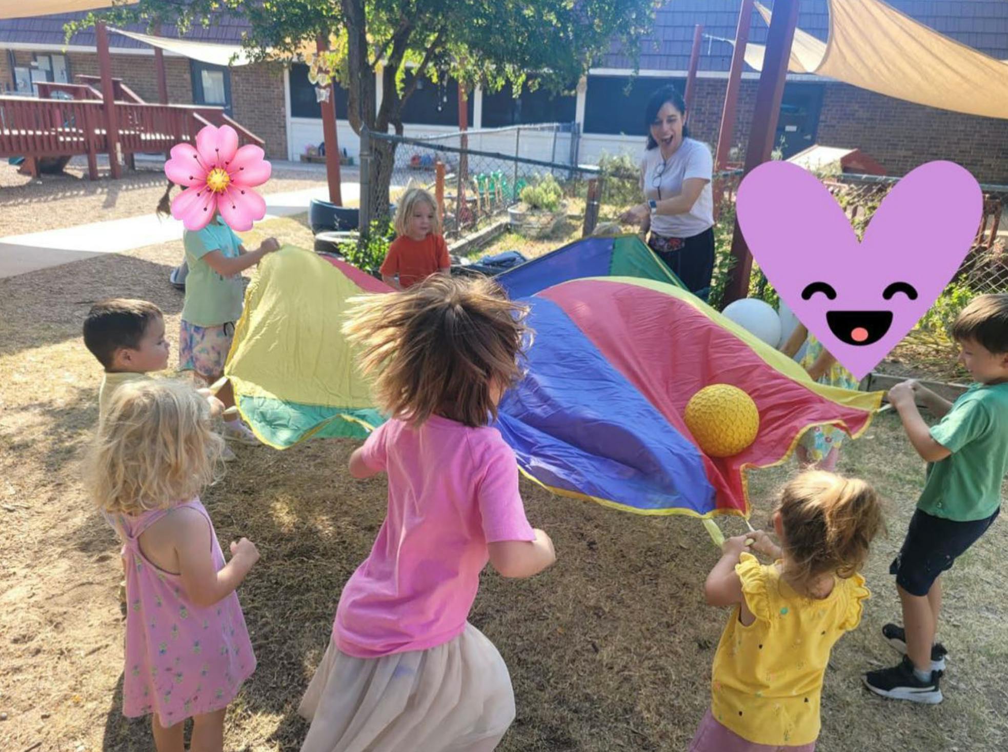 Children playing with a colorful parachute and a yellow ball outdoors