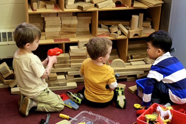 Three children playing with blocks on the floor