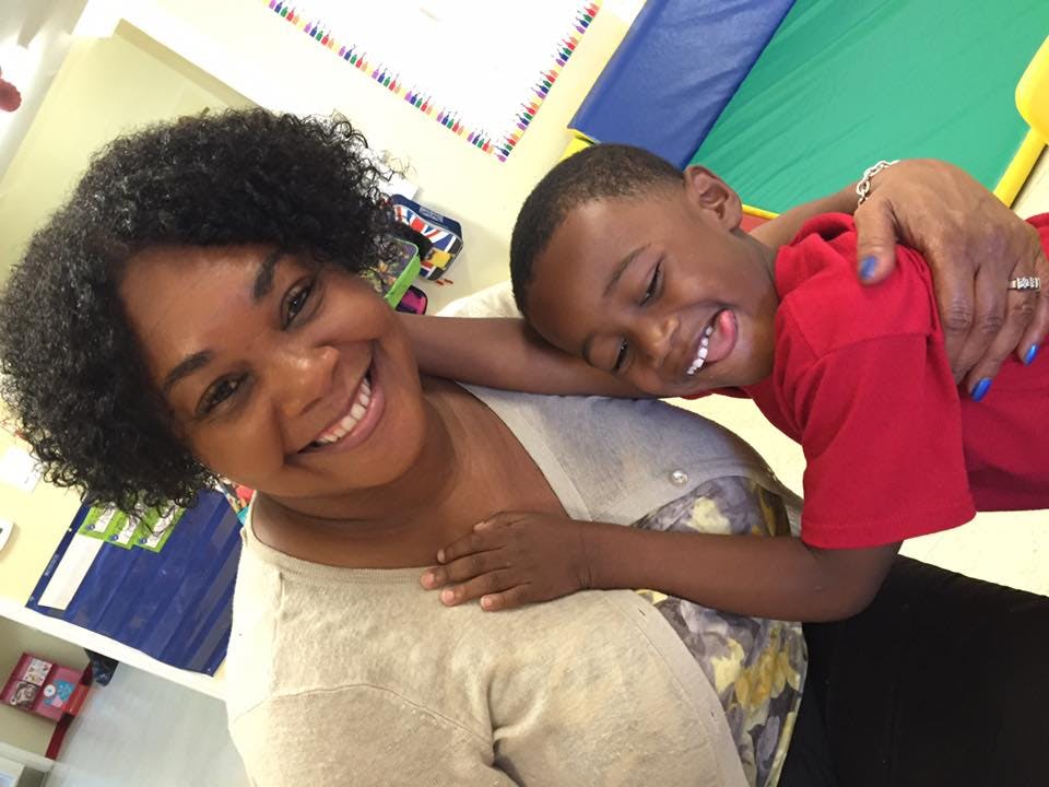 Person smiling with a child leaning on their shoulder