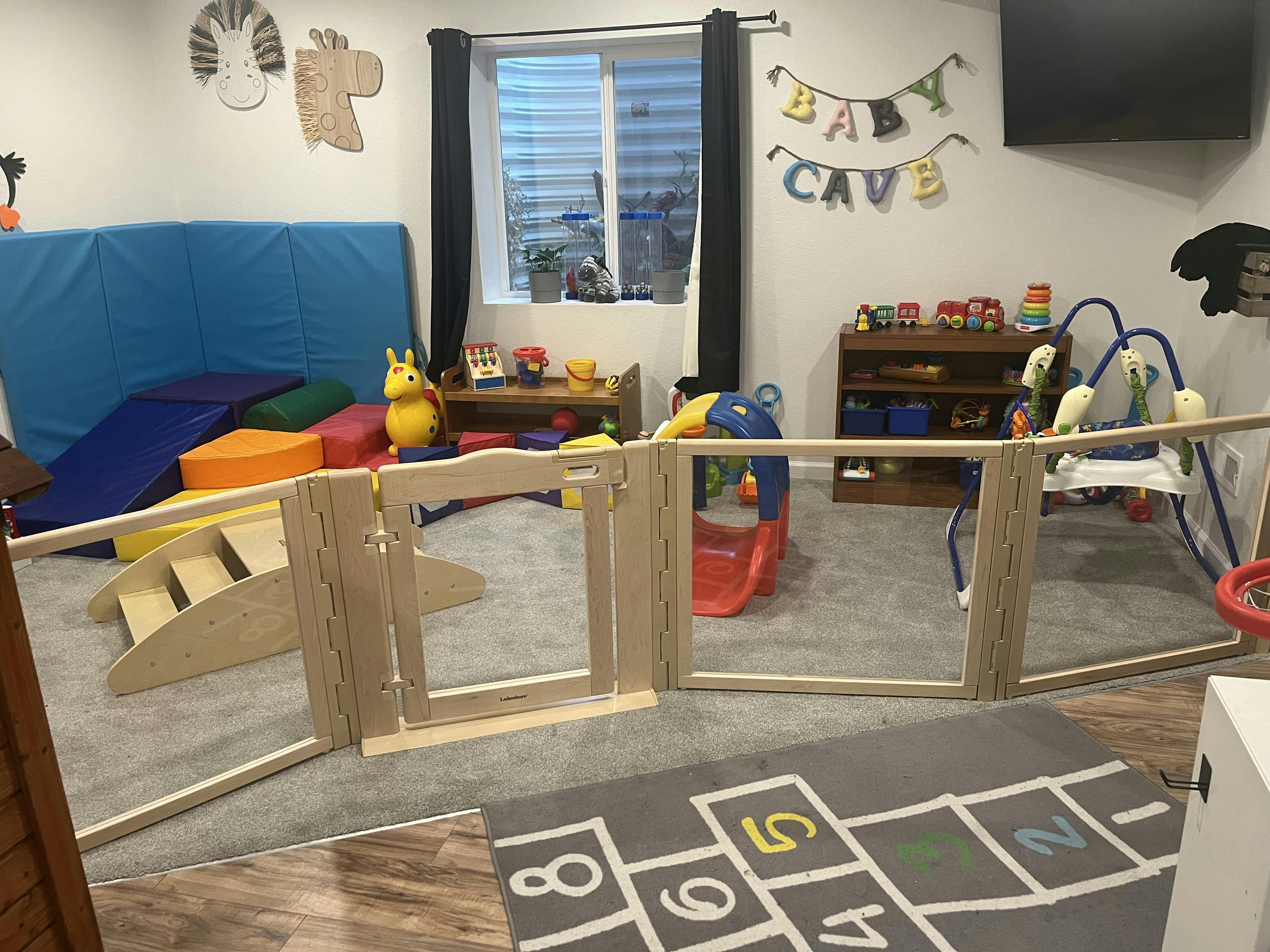 Playroom with soft climbing blocks, toys, and a baby gate