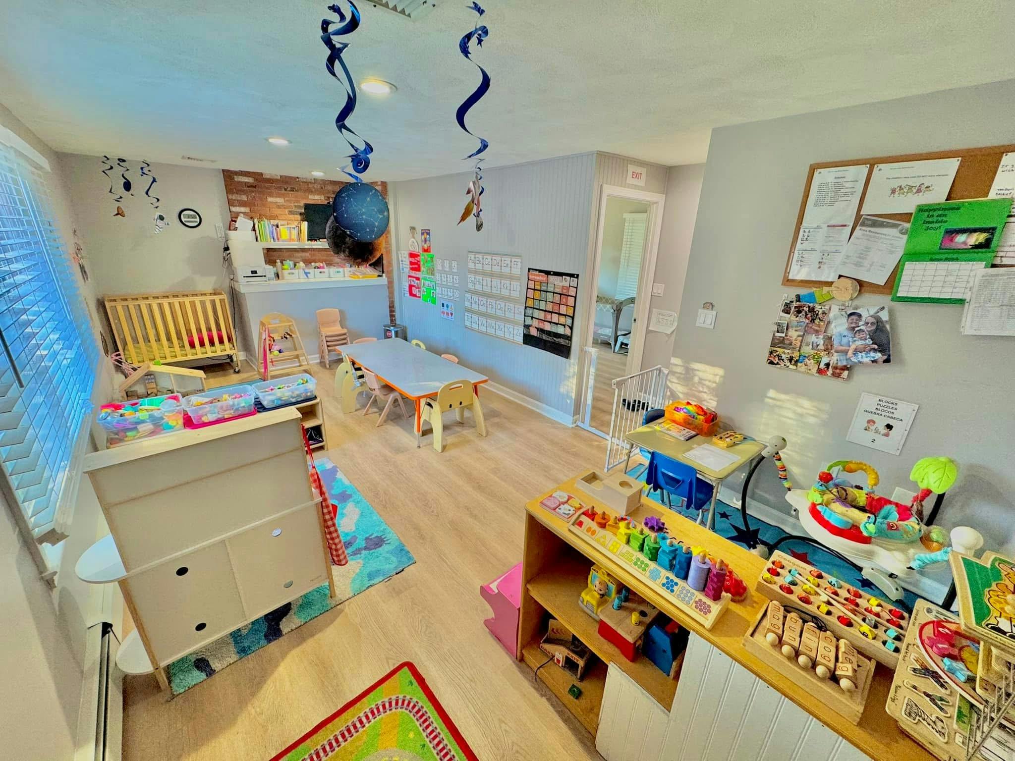 Playroom with small tables, chairs, crib, and shelves with toys