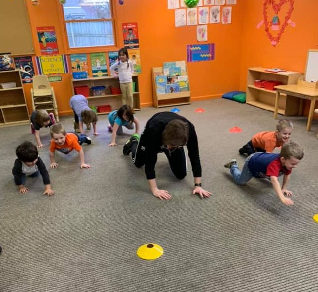 Adult and children crawling on the floor in a classroom