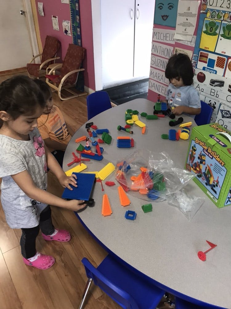 Two children playing with building blocks at a table in a classroom