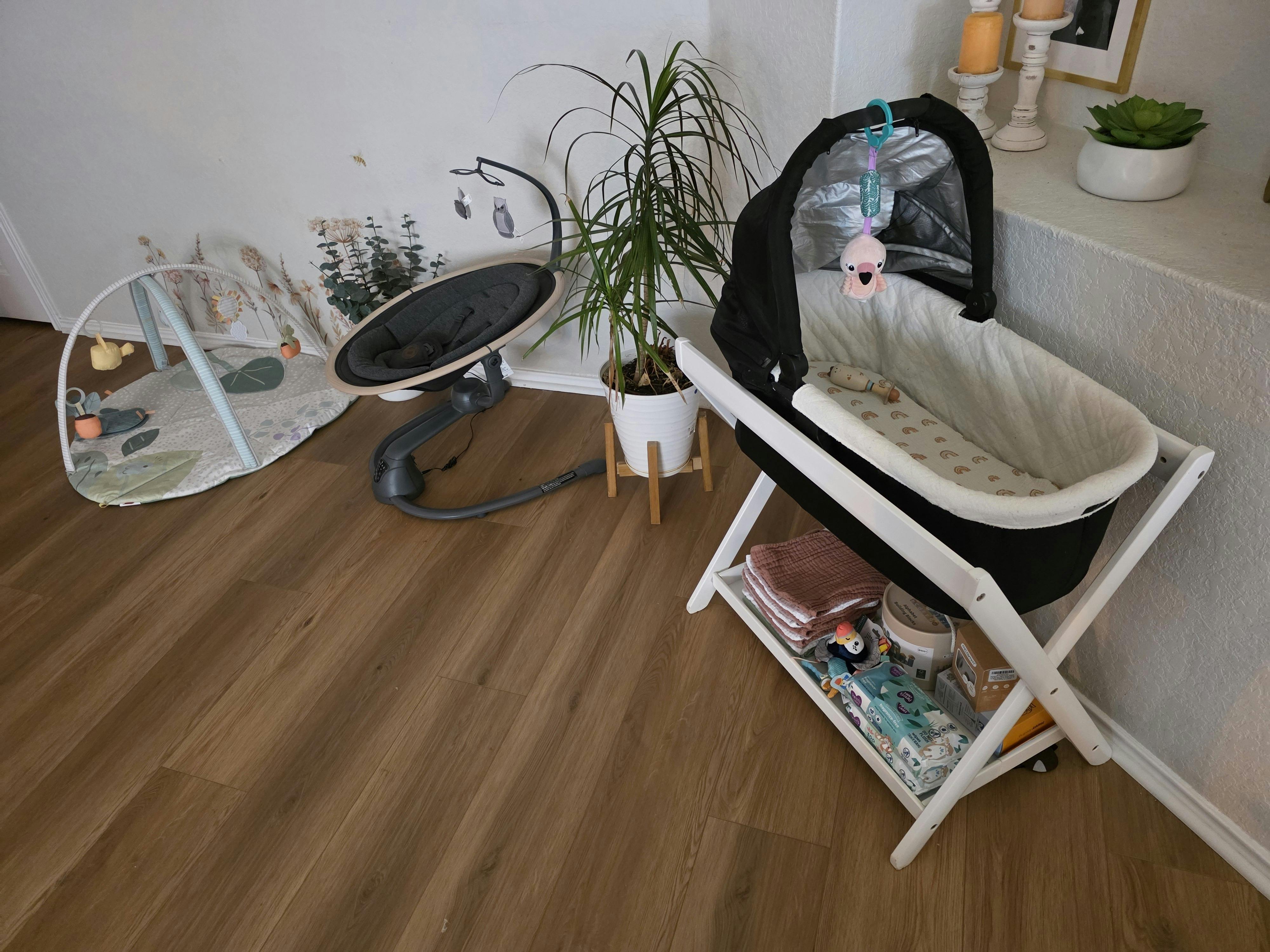 Baby bassinet, play mat, and infant rocker in a nursery