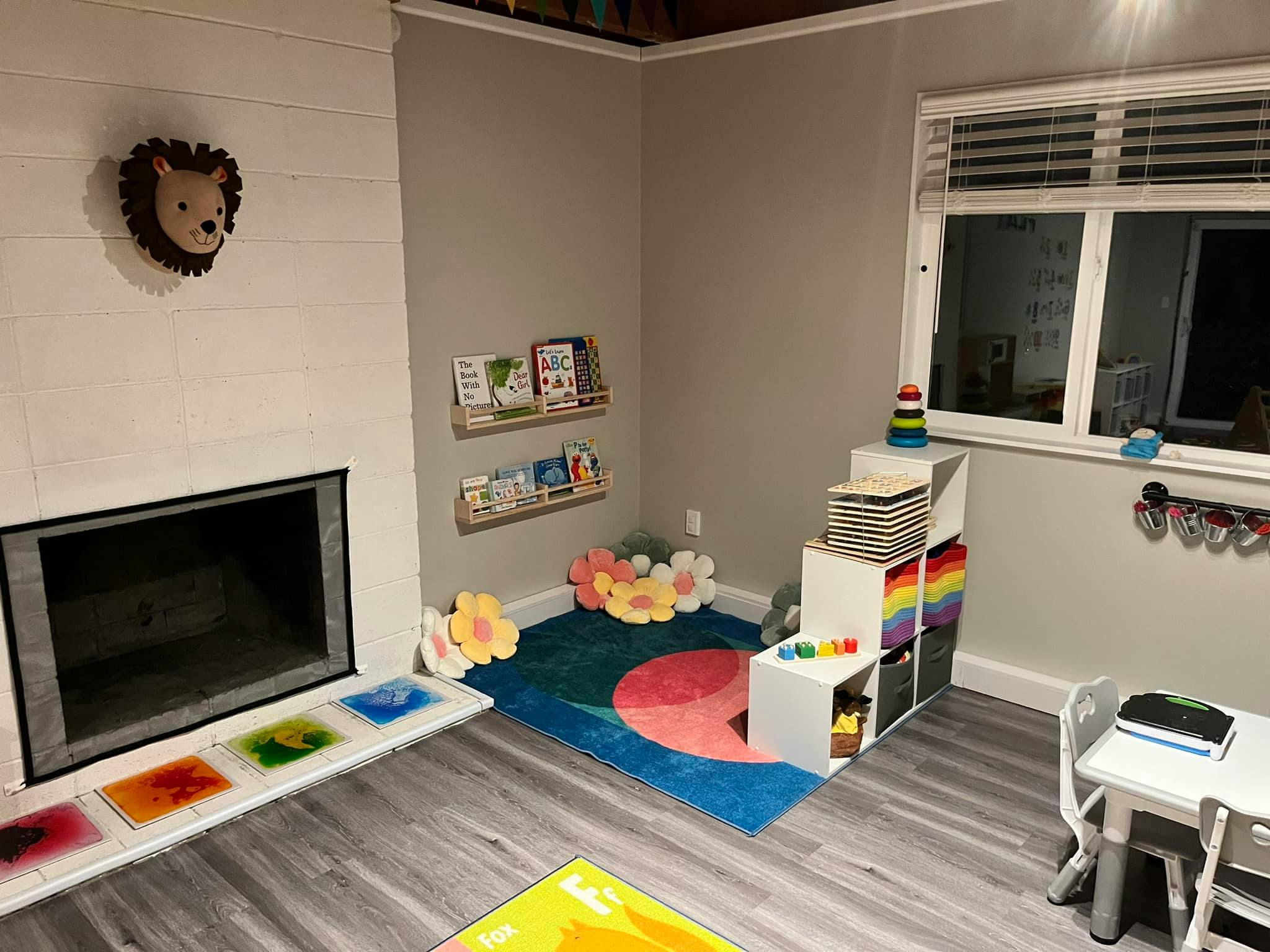 Playroom with a colorful rug, shelves of books, and a small table and chairs