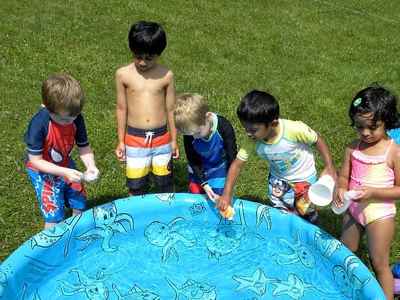 Children playing in a small blue wading pool