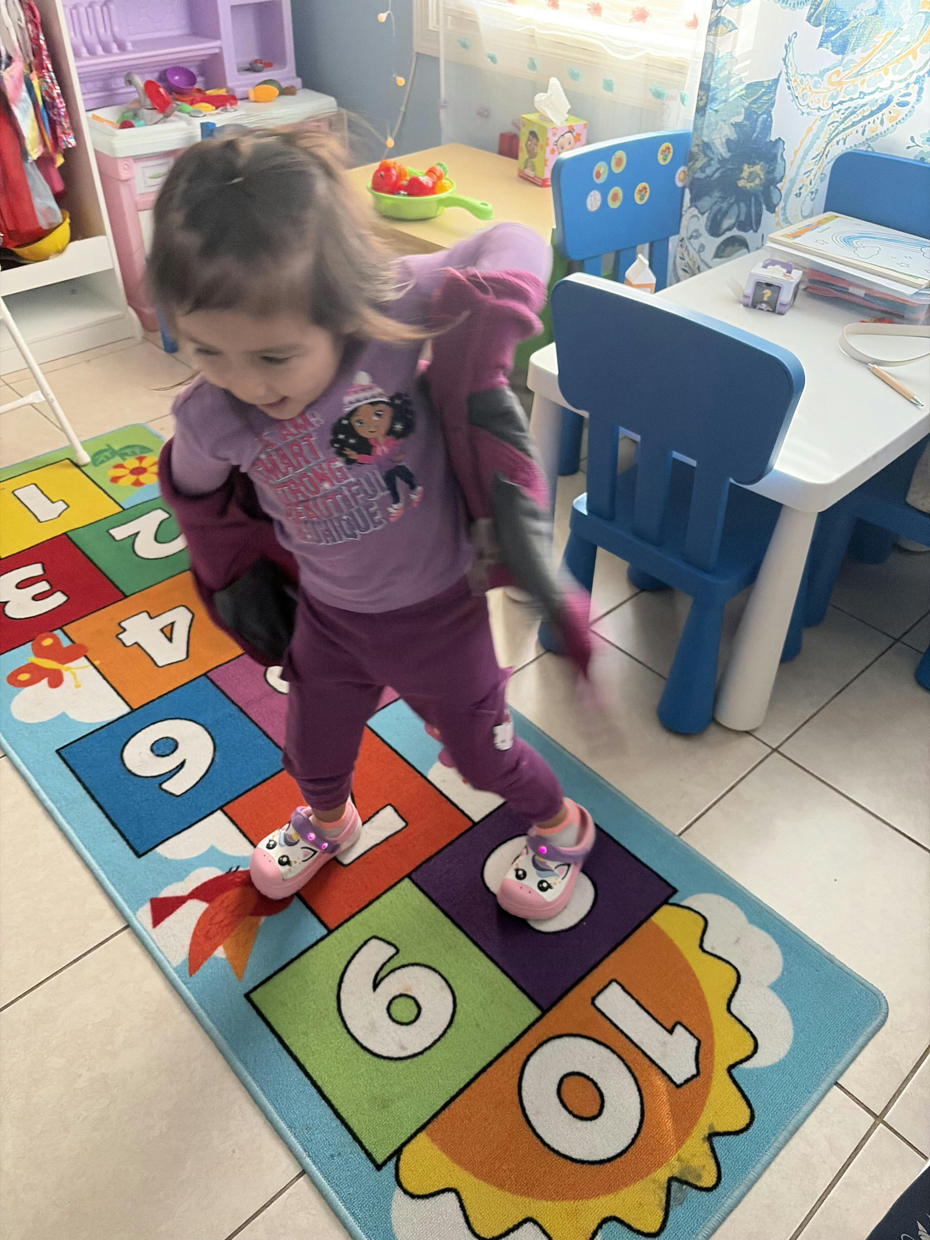 Child stepping on a colorful number rug in a playroom