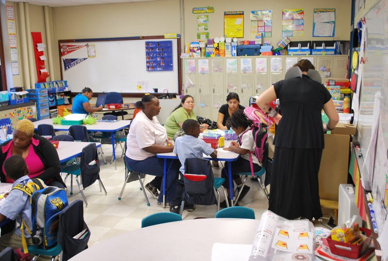 People and children sitting at tables in a classroom