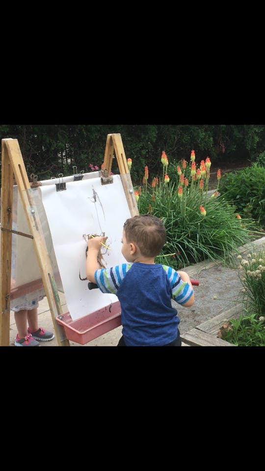 Child painting on an easel outdoors