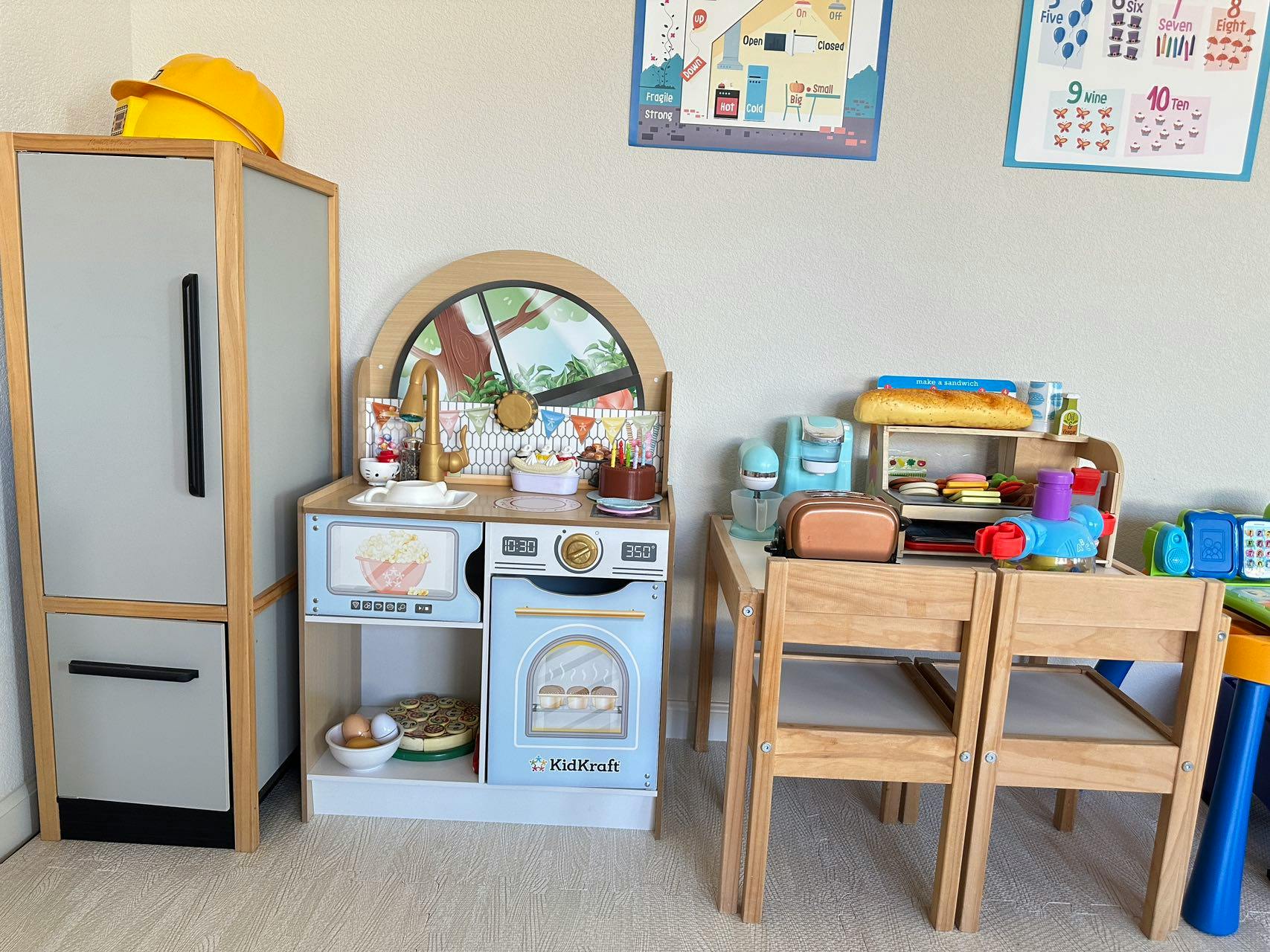 Play kitchen set with a refrigerator, stove, and small table with chairs