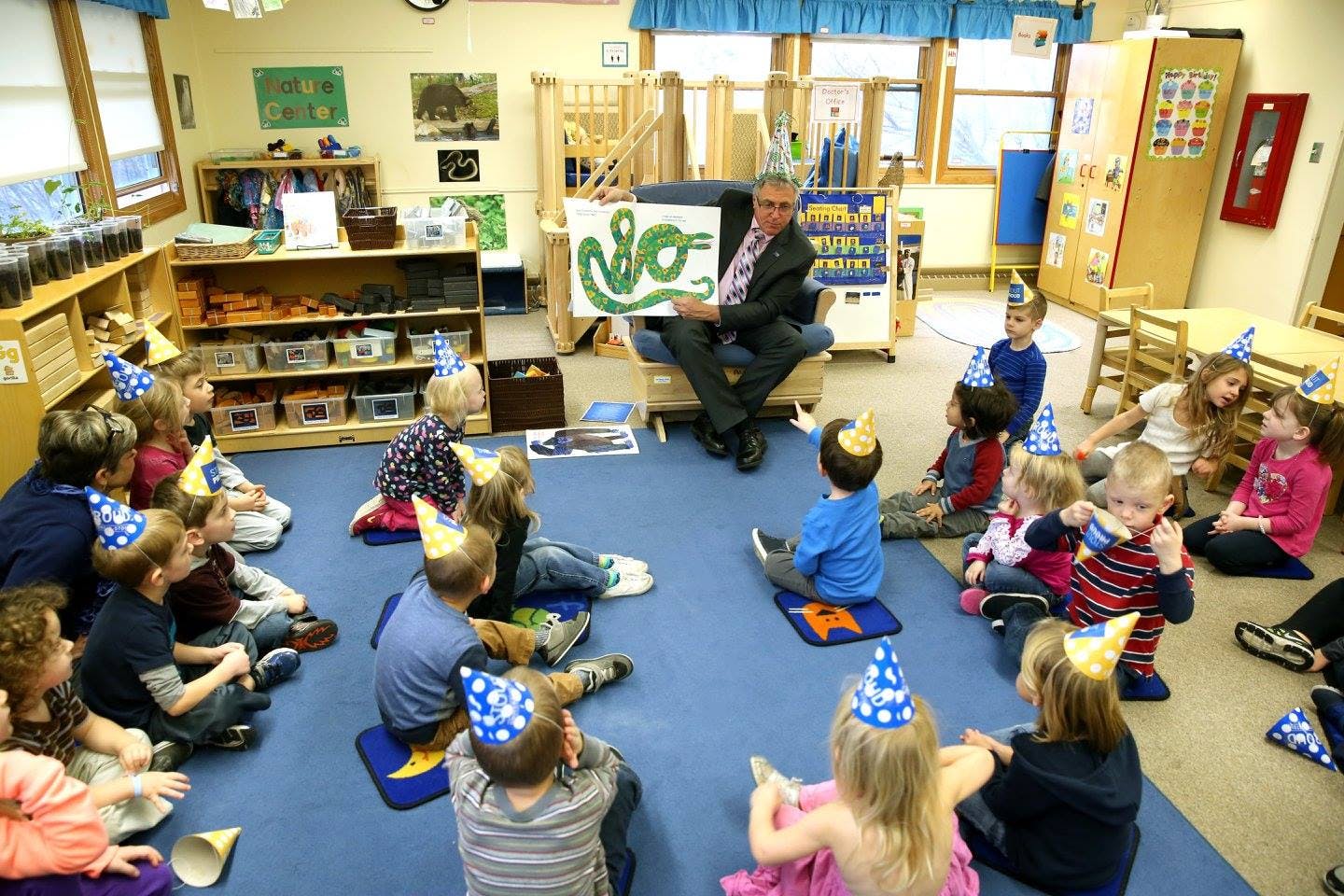 Person reading a book to children wearing party hats in a classroom