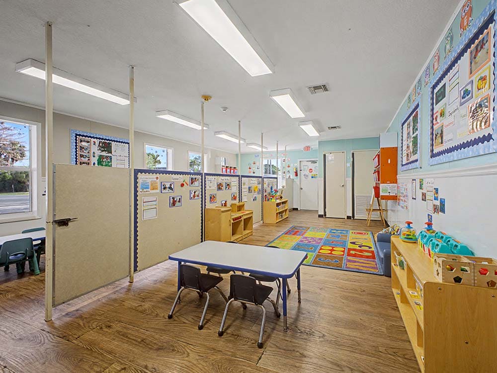 Empty colorful classroom with small tables, chairs, and learning materials