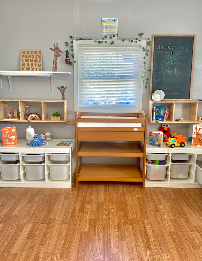 Classroom with shelves of toys, a changing table, and a chalkboard