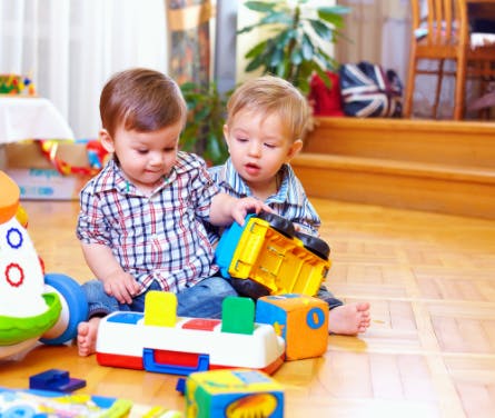 Two children playing with toys on a wooden floor