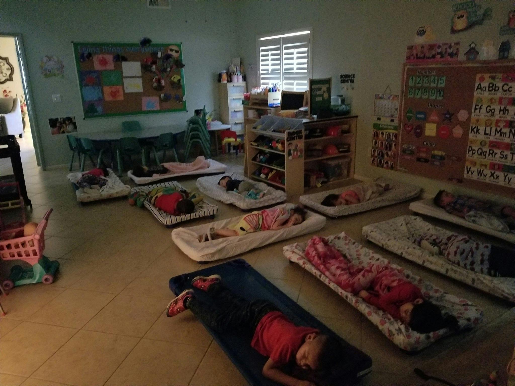 Children sleeping on mats in a classroom