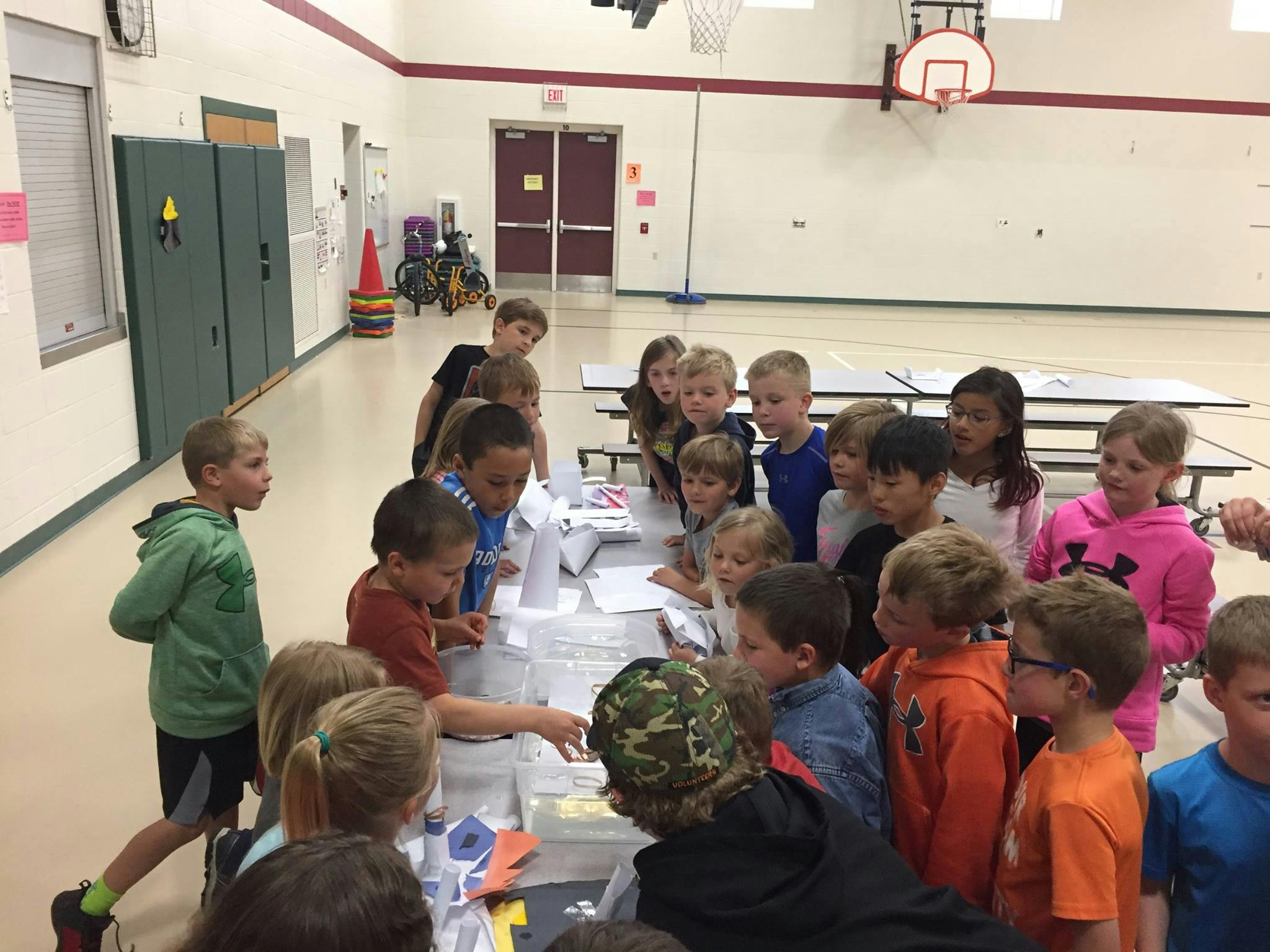 Children gathered around a table in a gymnasium