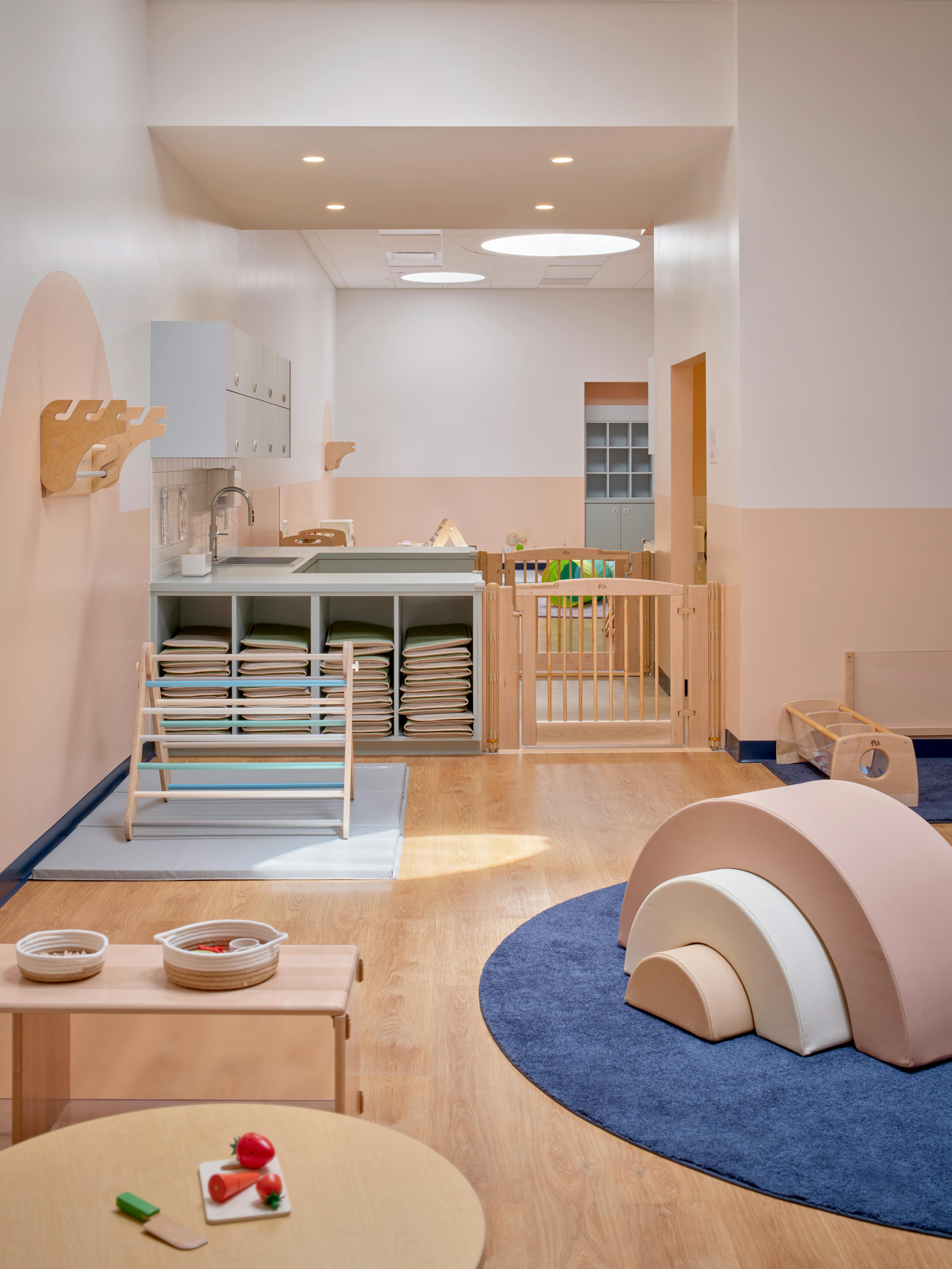 Children's play area with soft play equipment, small tables, and storage