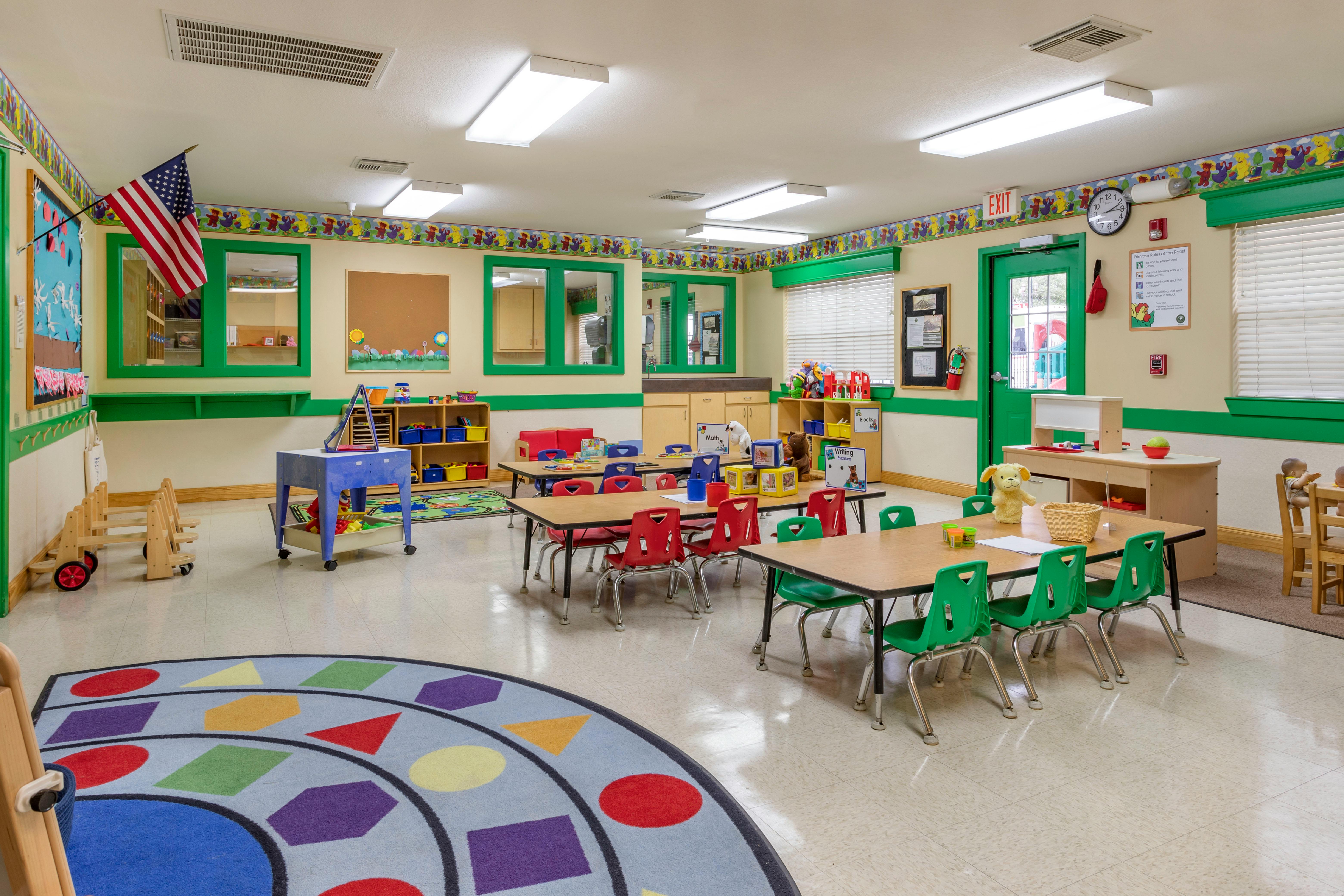 Classroom with small tables, colorful chairs, and a patterned rug
