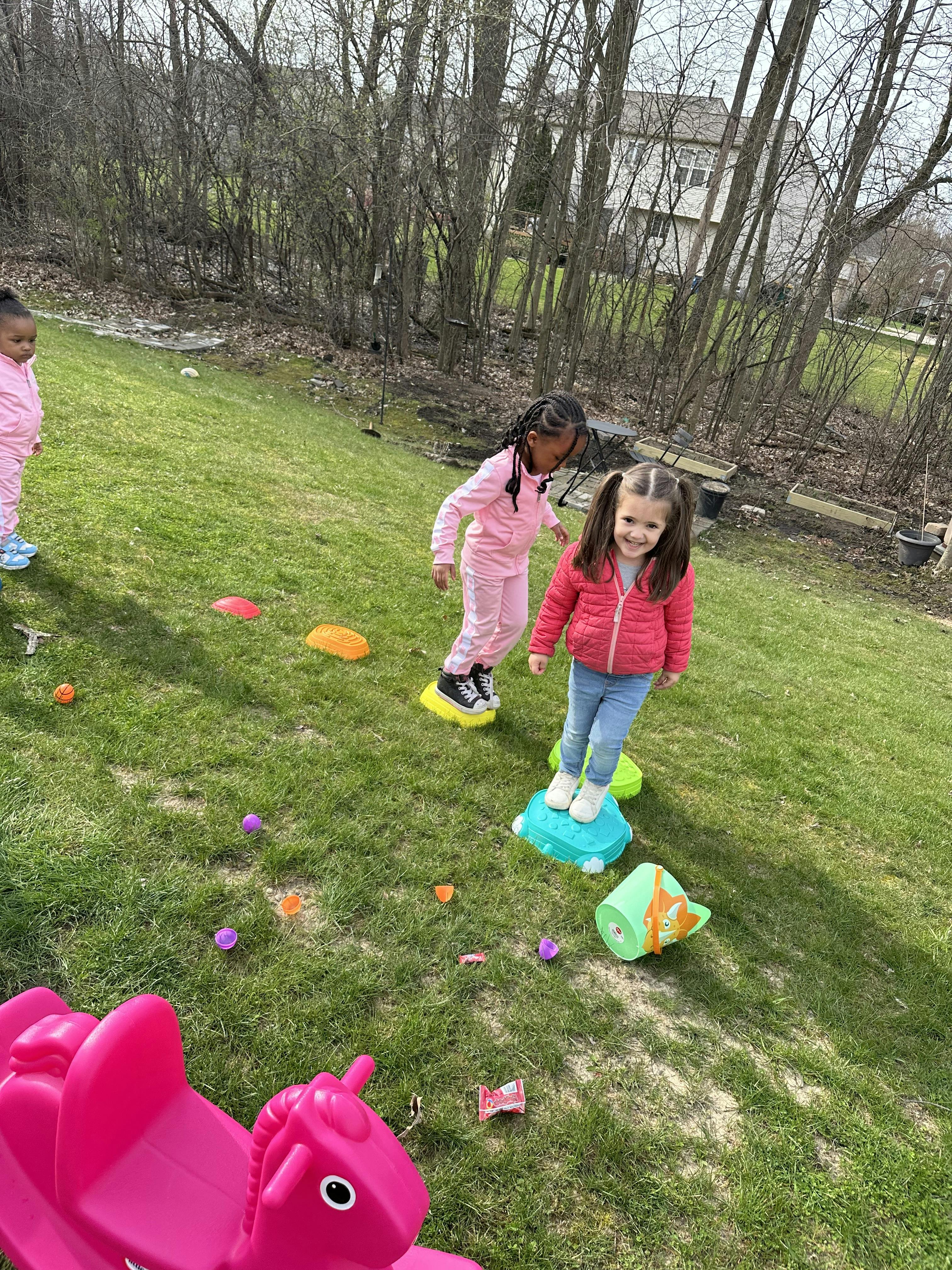 Two children playing on stepping stones in a grassy area