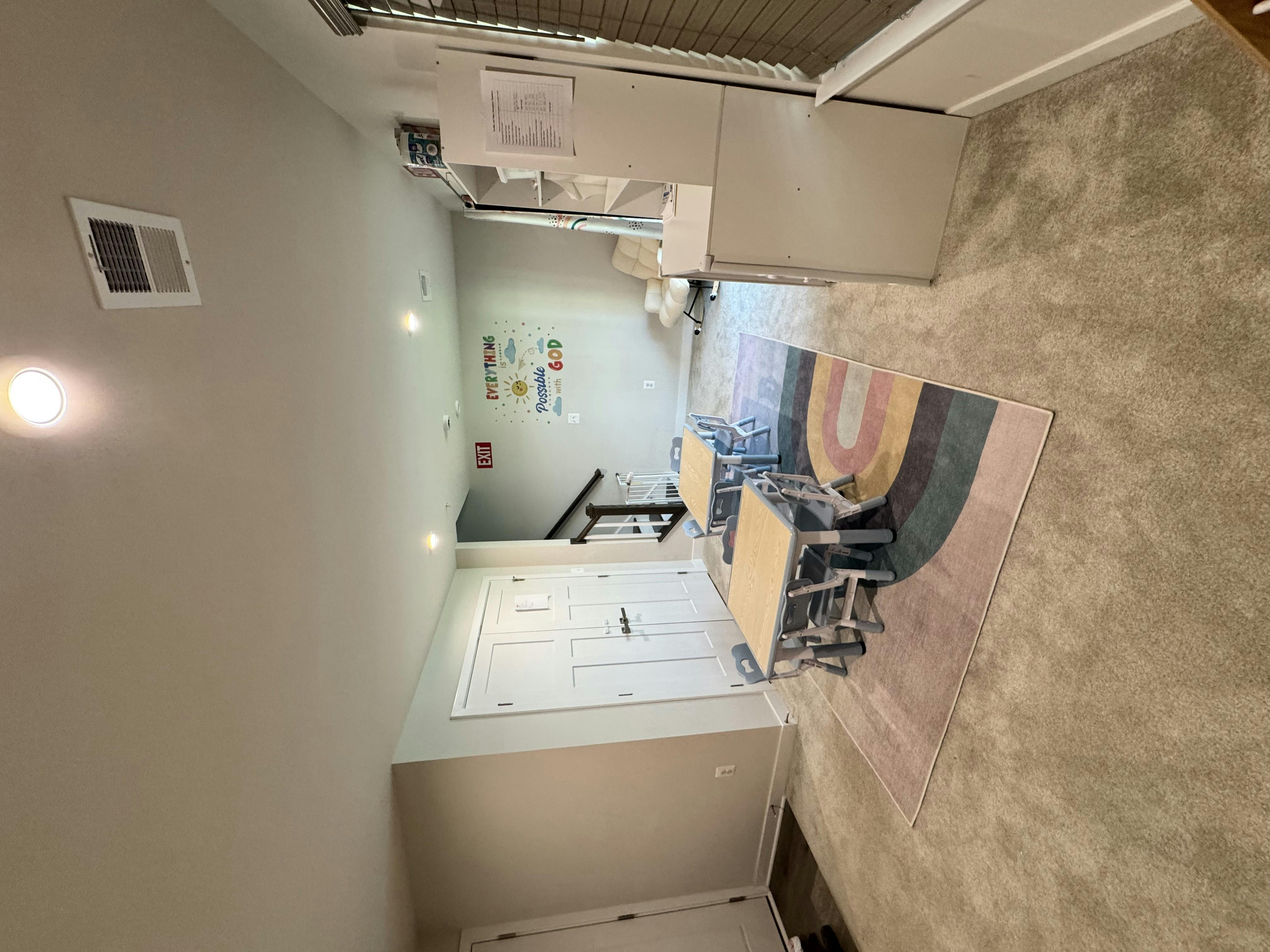 A room with a rug, two small tables, and chairs