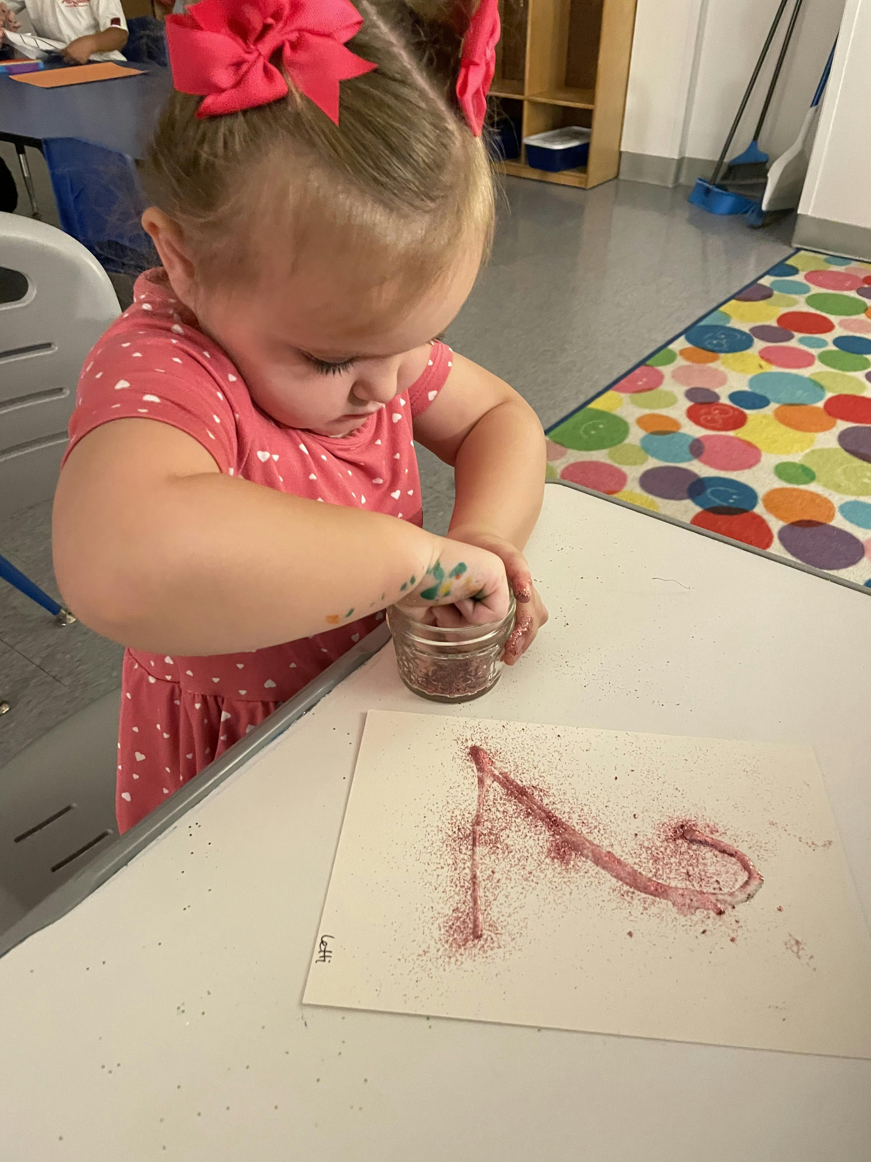 Child creating art with glitter on paper