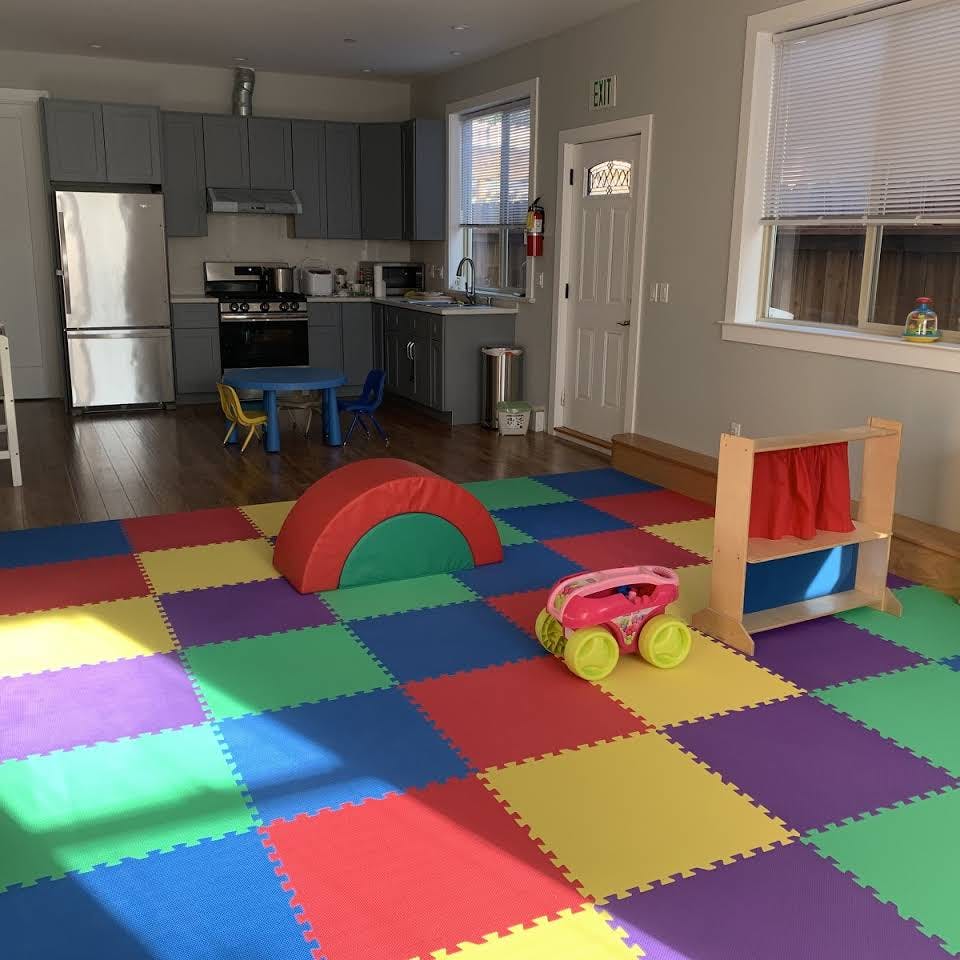 Playroom with colorful floor mats, soft play equipment, and a small toy