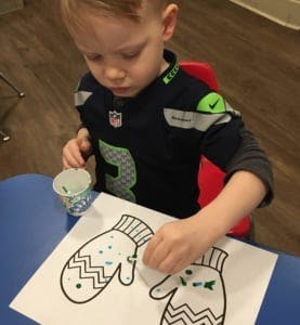 Child decorating a paper mitten with paint