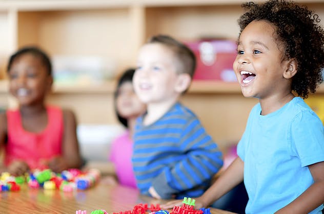 Children sitting at a table with colorful blocks