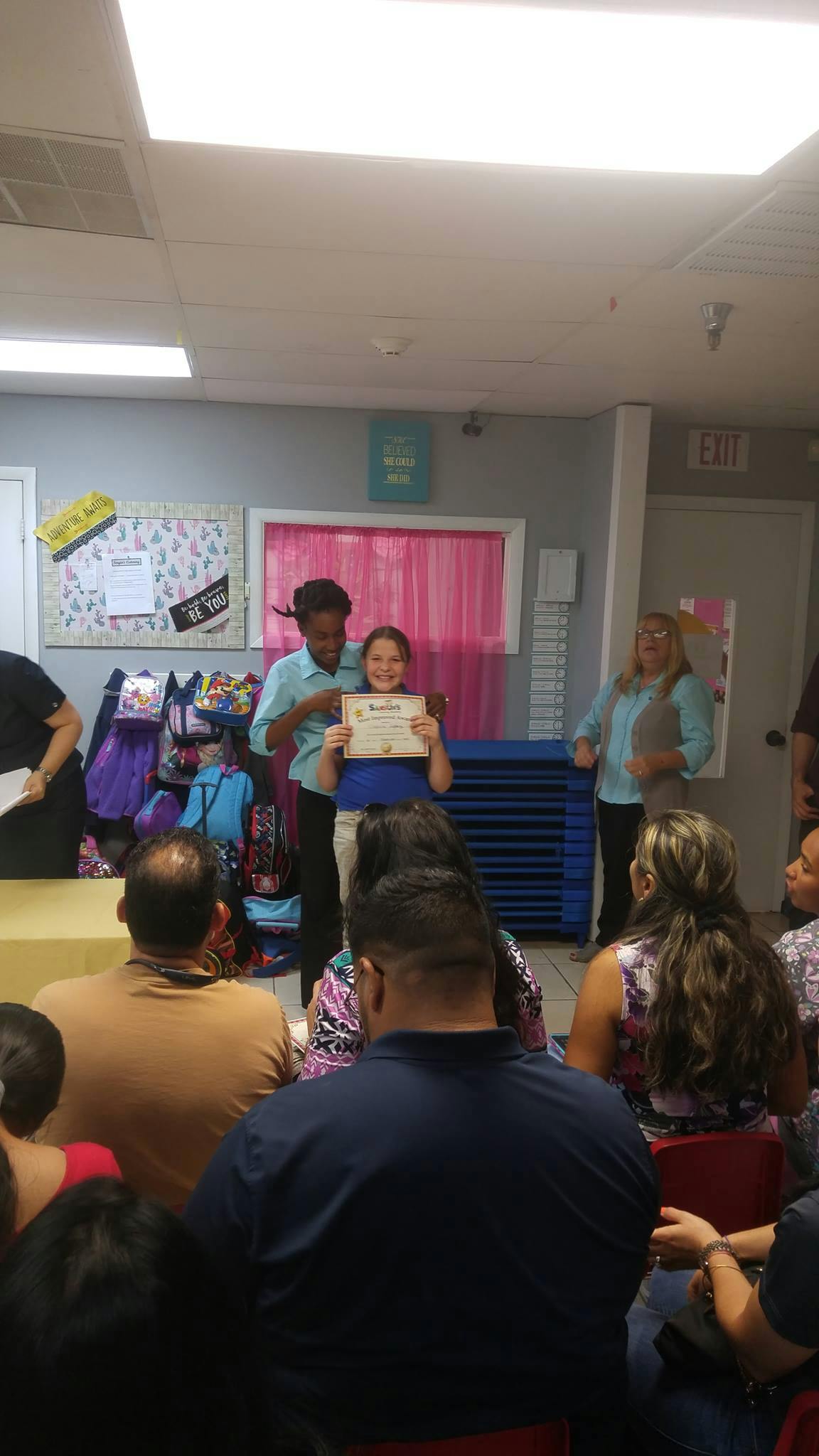 Person presenting a certificate to a child in front of an audience
