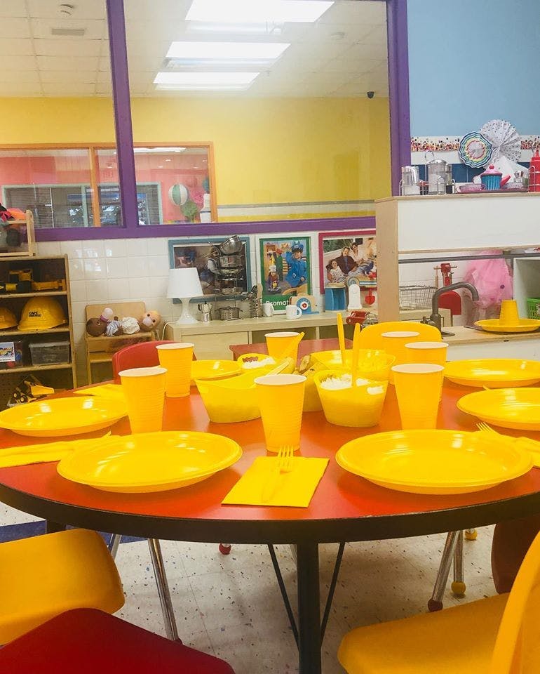 Table set with yellow plates, cups, and bowls in a classroom