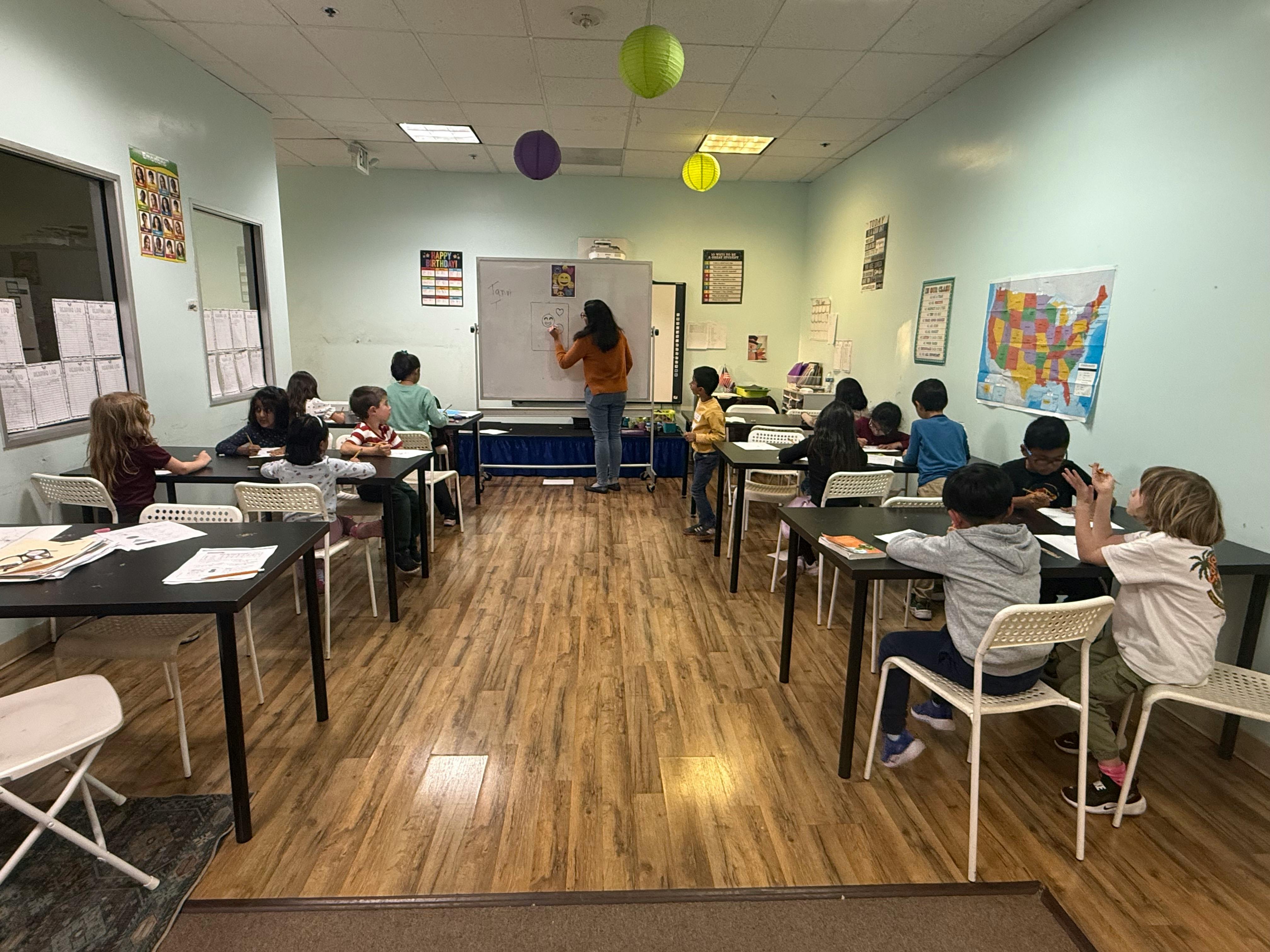 A person teaching a group of children seated at desks in a classroom