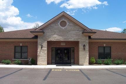 Front exterior of a brick building with a stone entrance under a blue sky