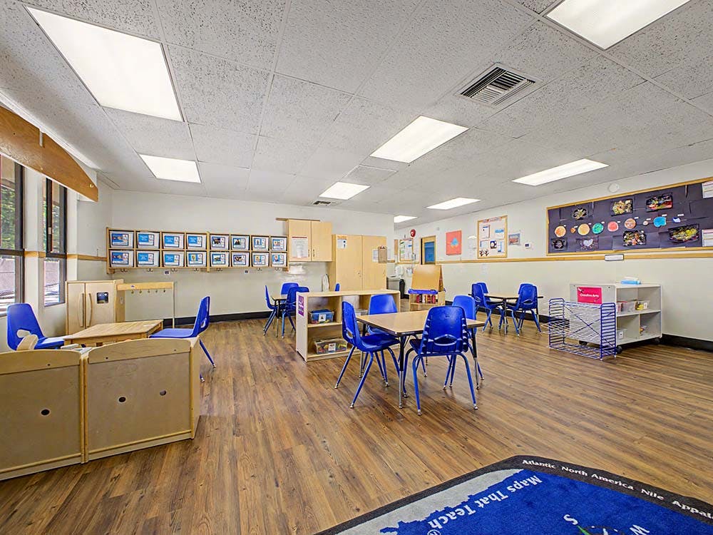 Classroom with small tables and chairs, and learning materials on walls and shelves