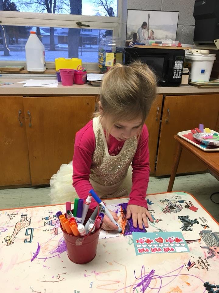 Child coloring at a table with markers