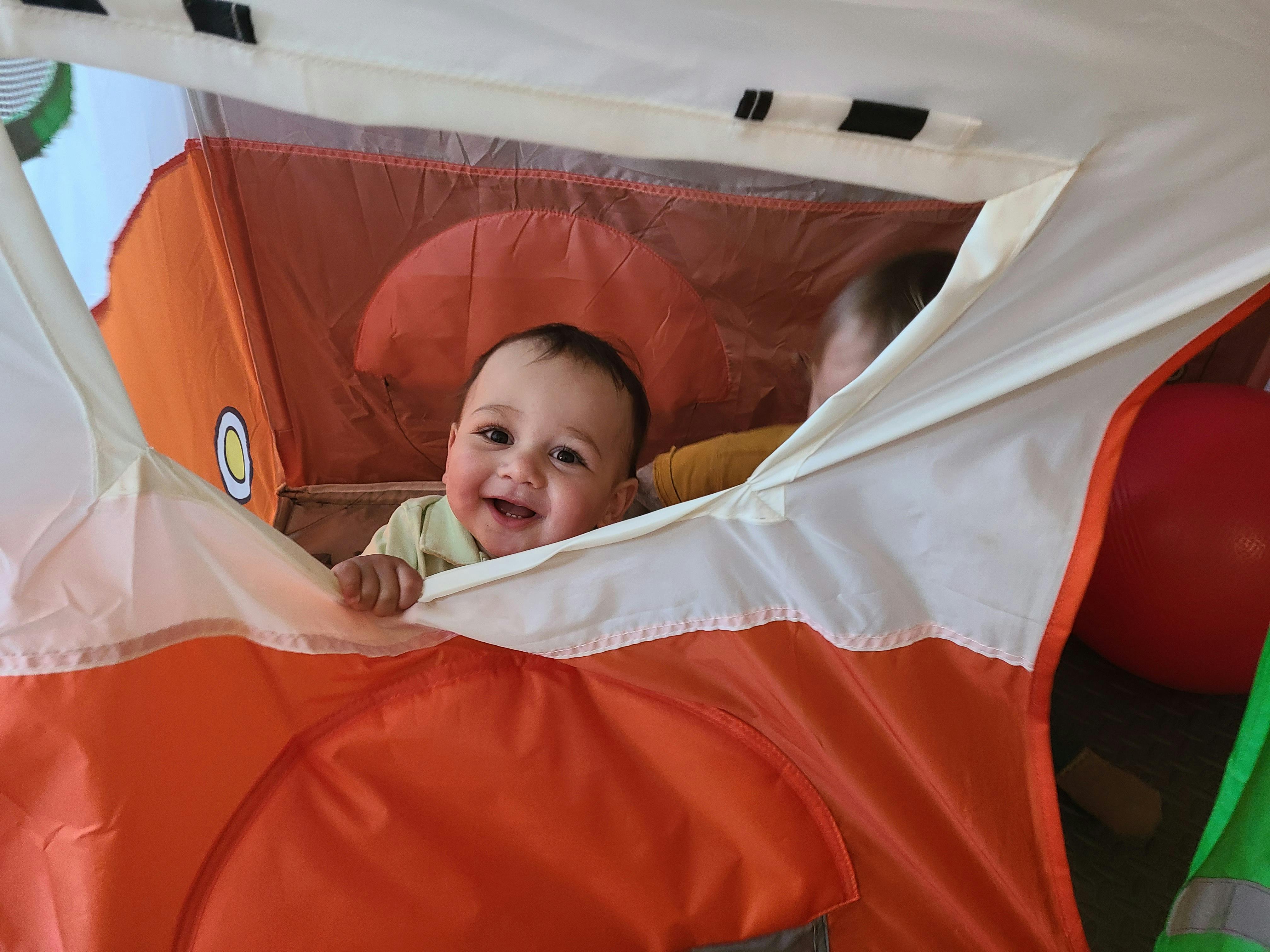 Child looking out from inside a play tent