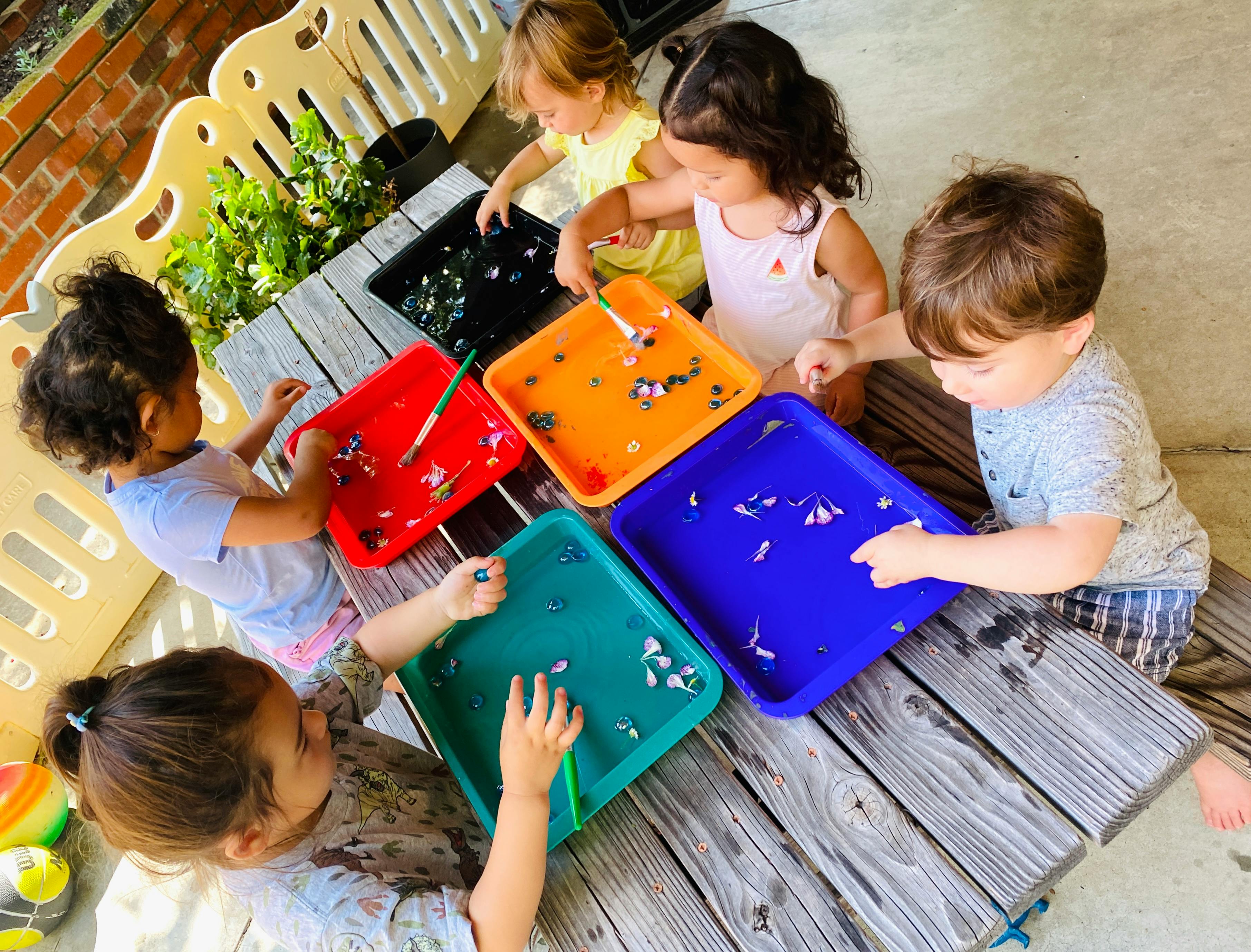 Children playing with colorful trays on a wooden table