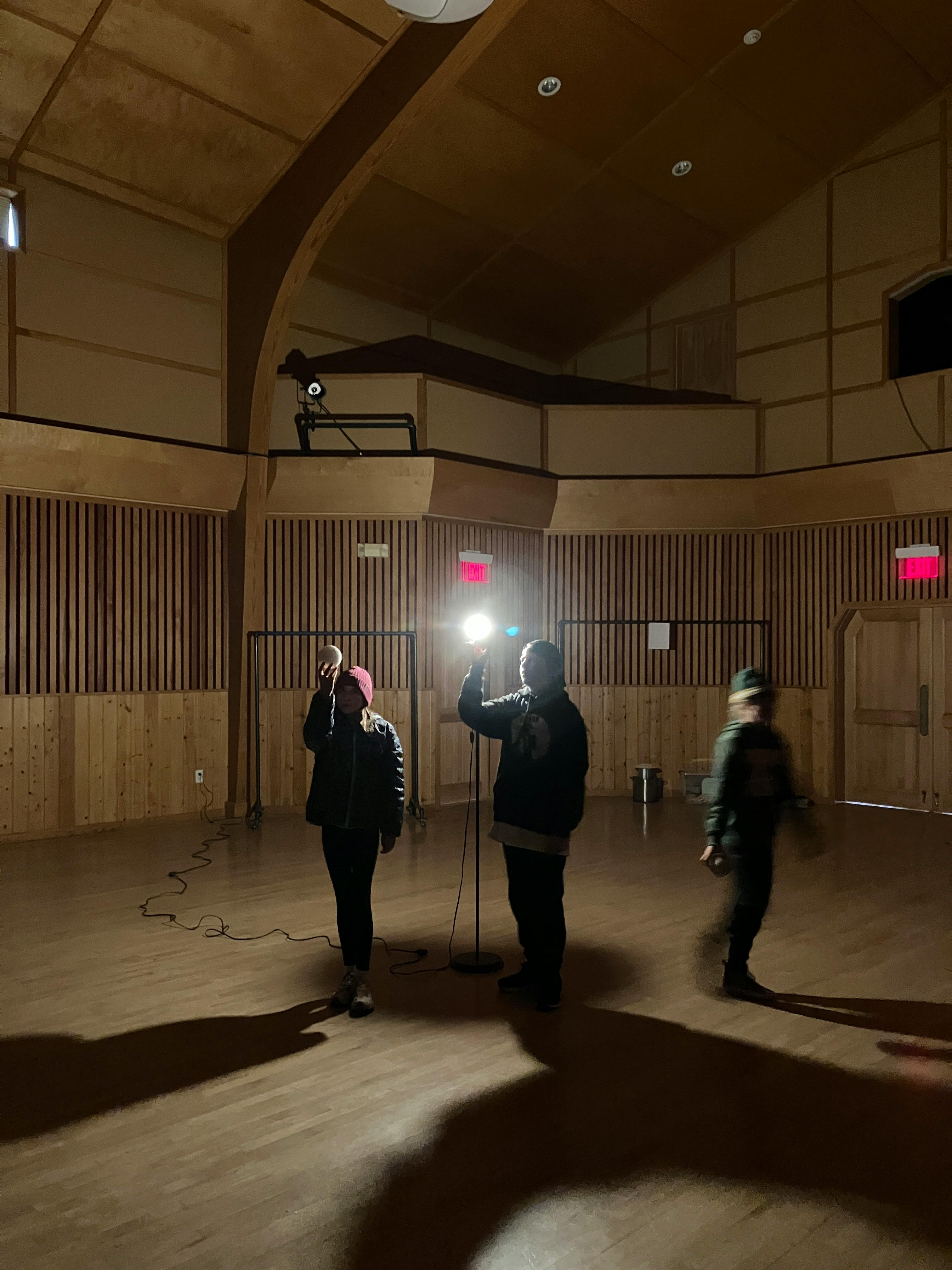 Three people in a large room with one person holding a microphone