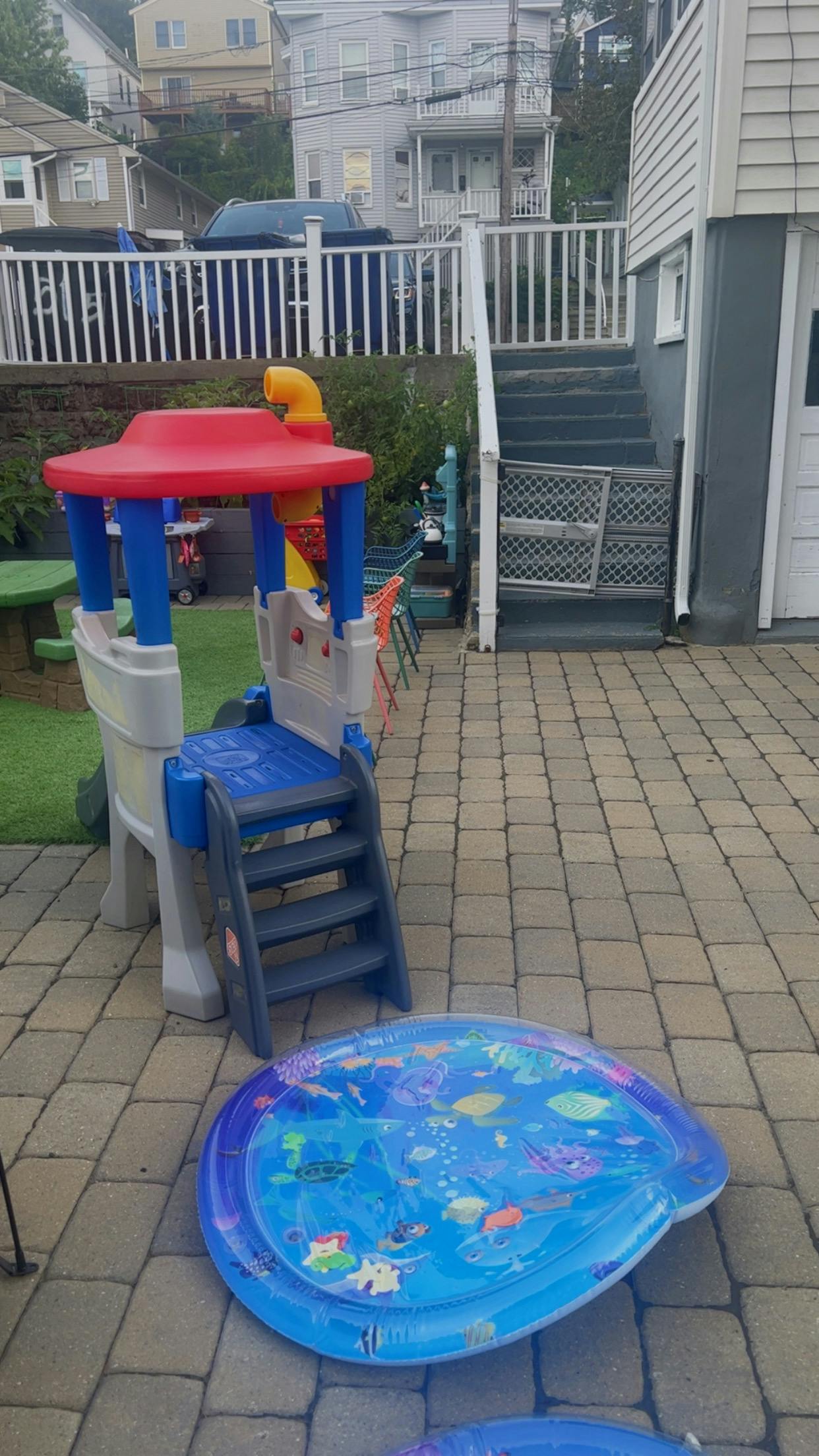 Play structure with slide and inflatable pool on a paved patio